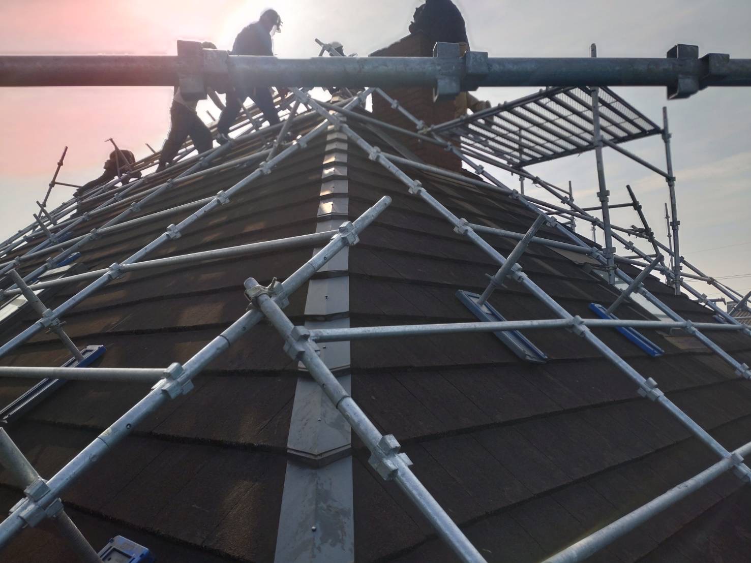 足場を組んだ屋根の上で作業する株式会社ふじのの職人たち